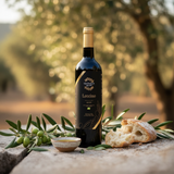 Tastefully Olive Leccino olive oil bottle with olive branches, rustic bread, and a bowl of oil in an olive grove.