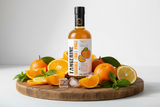Tastefully Olive Tangerine crushed fruit puree bottle on a wooden board with citrus halves, wedges, mint, and ice cubes.