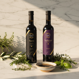 Tastefully Olive Tuscan Herb olive oil and Traditional dark balsamic bottles with rosemary, thyme, basil, and a dipping bowl.