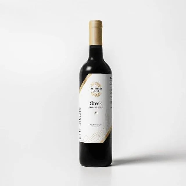 Tastefully Olive Greek Seasoning white balsamic vinegar bottle with a white label and gold cap on a white background.